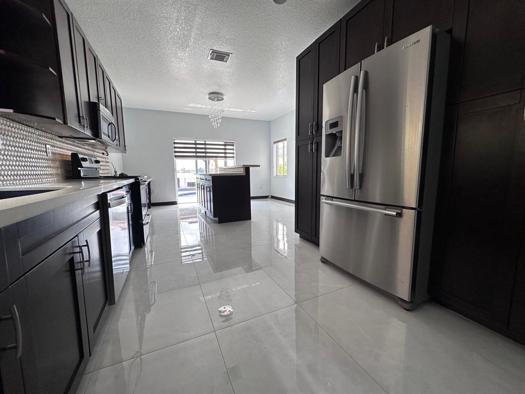 14024 Southwest 132nd Avenue Miami, FL 33186 - Photo 13 of 24 a kitchen with stainless steel appliances granite countertop a refrigerator a stove a sink and a microwave