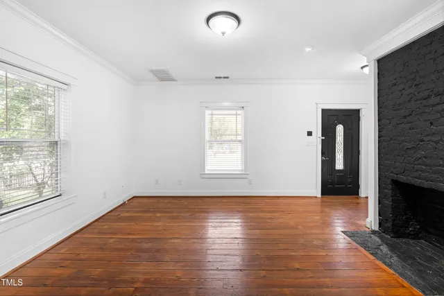 an empty room with wooden floor and fireplace