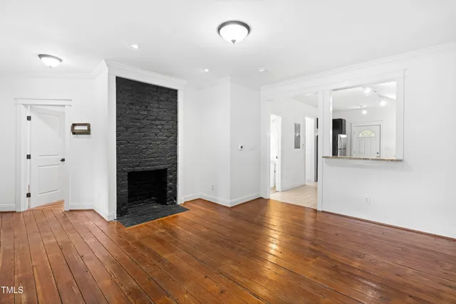 a view of a kitchen and an empty room with wooden floor
