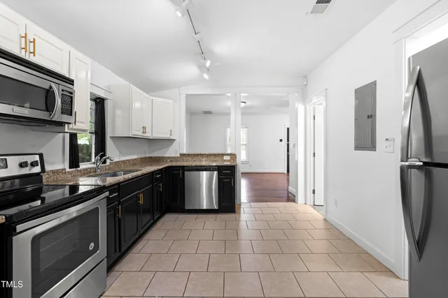 a kitchen with stainless steel appliances granite countertop a refrigerator a sink a stove top oven and a counter space