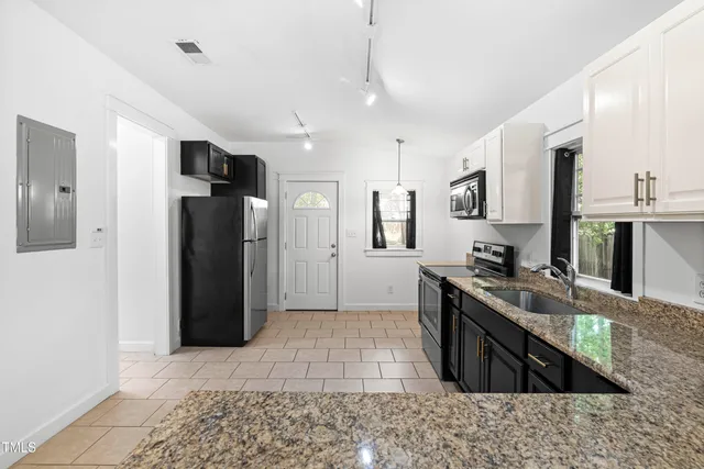 a kitchen with stainless steel appliances granite countertop a refrigerator a stove and a sink
