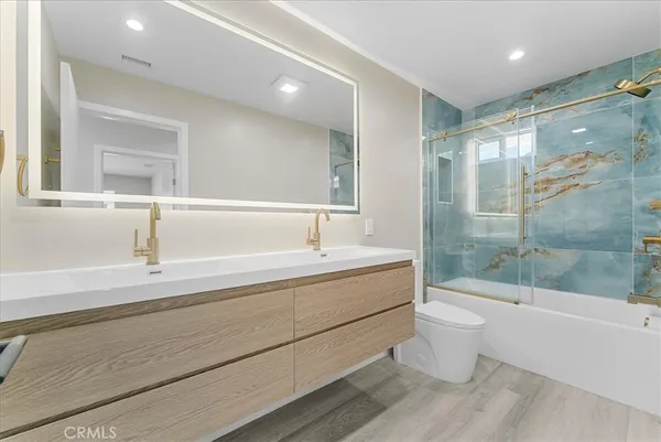 a bathroom with a bathtub shower sink mirror and toilet