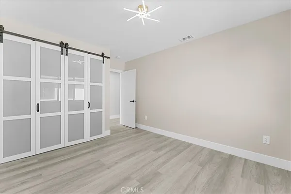 a view of an empty room with wooden floor and closet
