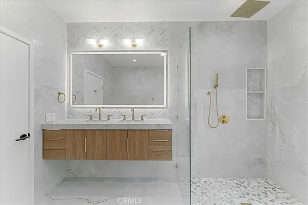 a bathroom with a sink a toilet a mirror and shower