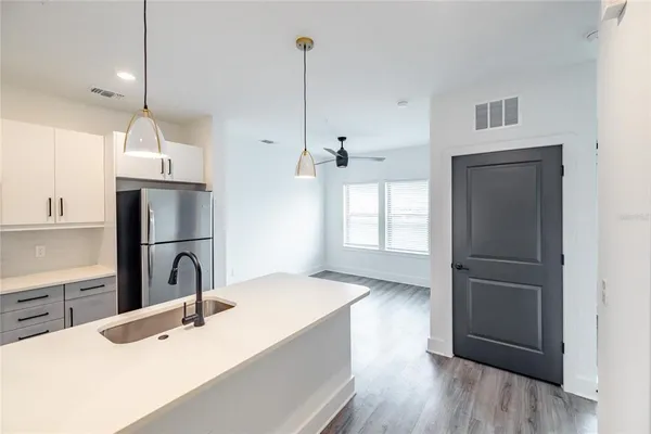 a kitchen with kitchen island a sink appliances wooden floor and a counter top space