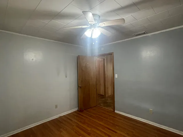 an empty room with wooden floor chandelier fan and closet area