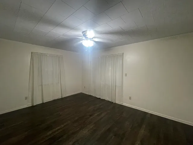 an empty room with wooden floor and fan