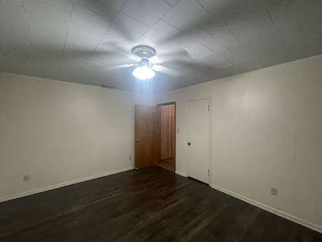 an empty room with wooden floor and fan