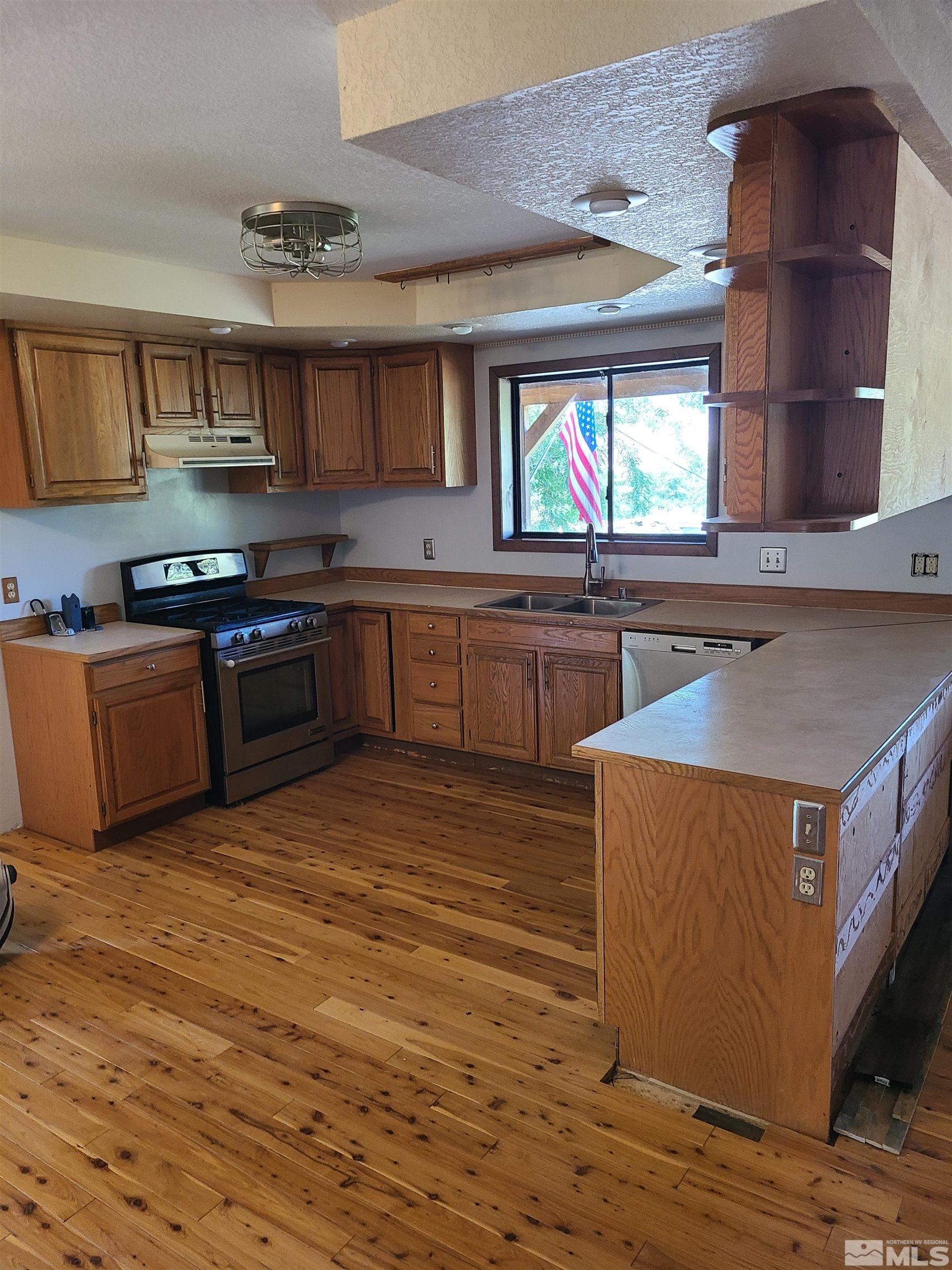 14460 Virginia Foothills Drive Reno, NV 89521 - Photo 5 of 17 a kitchen with stainless steel appliances granite countertop a sink counter space and wooden floor