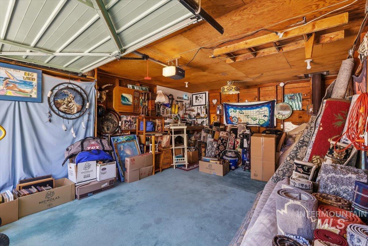 4619 Freemont Street Boise, ID 83706 - Photo 22 of 27 Garage interior featuring wood panel walls, a painted overhead door, and a light blue carpeted floor