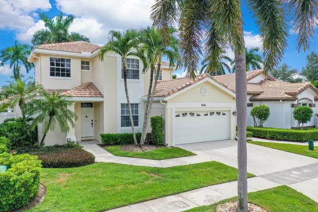 a view of a white house with a yard and palm trees