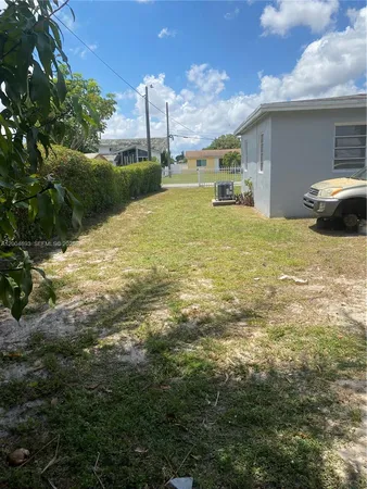 a view of a large yard with plants and large trees