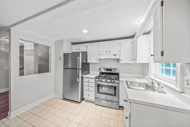 a kitchen with white cabinets stainless steel appliances and a window
