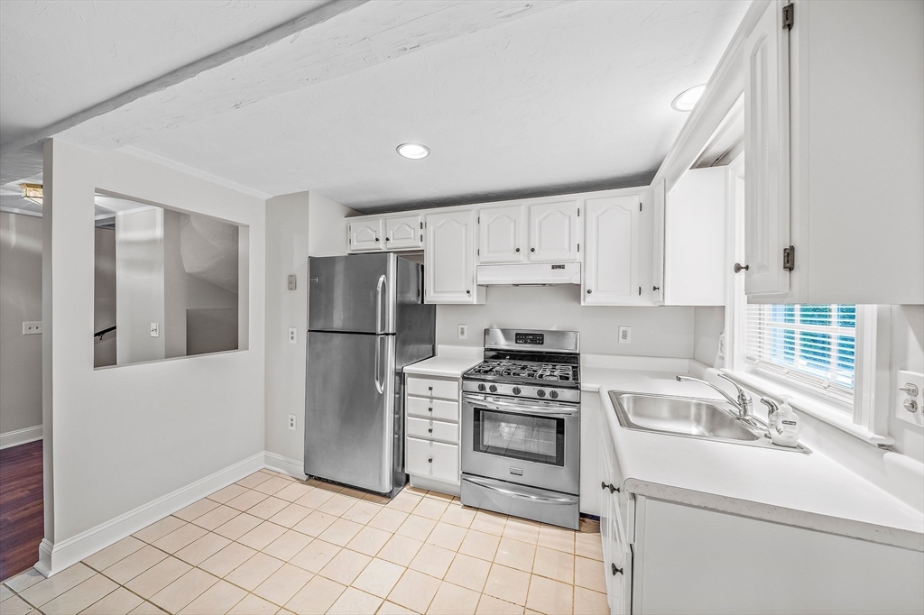 a kitchen with white cabinets stainless steel appliances and a window
