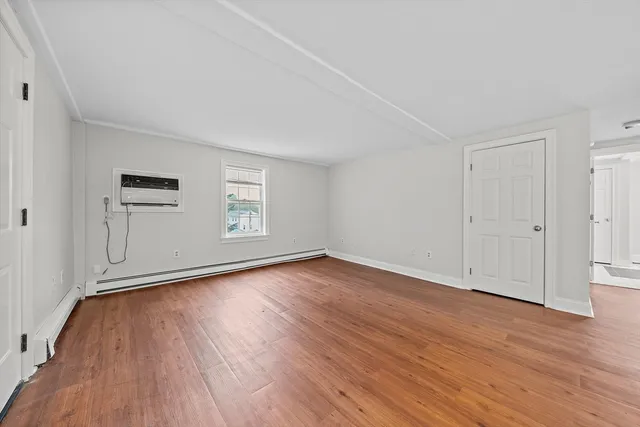 a view of empty room with wooden floor and window