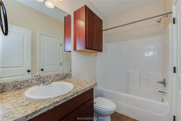 a bathroom with a granite countertop sink toilet and shower