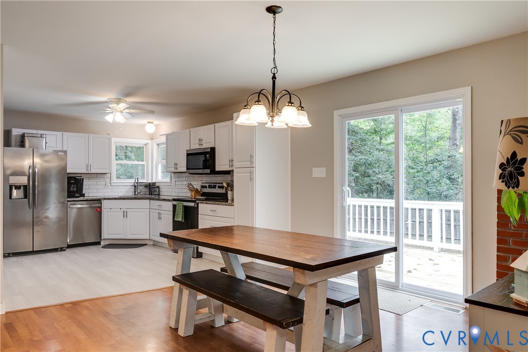1030 Rock Spring Road Bumpass, VA 23024 - Photo 10 of 34 a kitchen with refrigerator a stove a sink dishwasher a dining table and chairs with wooden floor