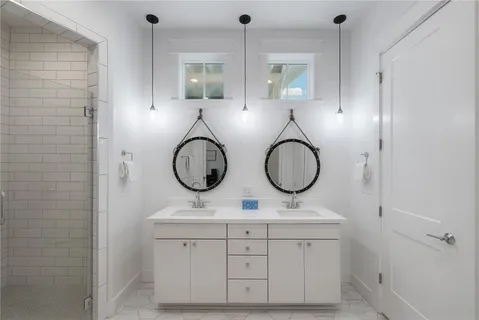 a bathroom with a double vanity sink mirror and shower