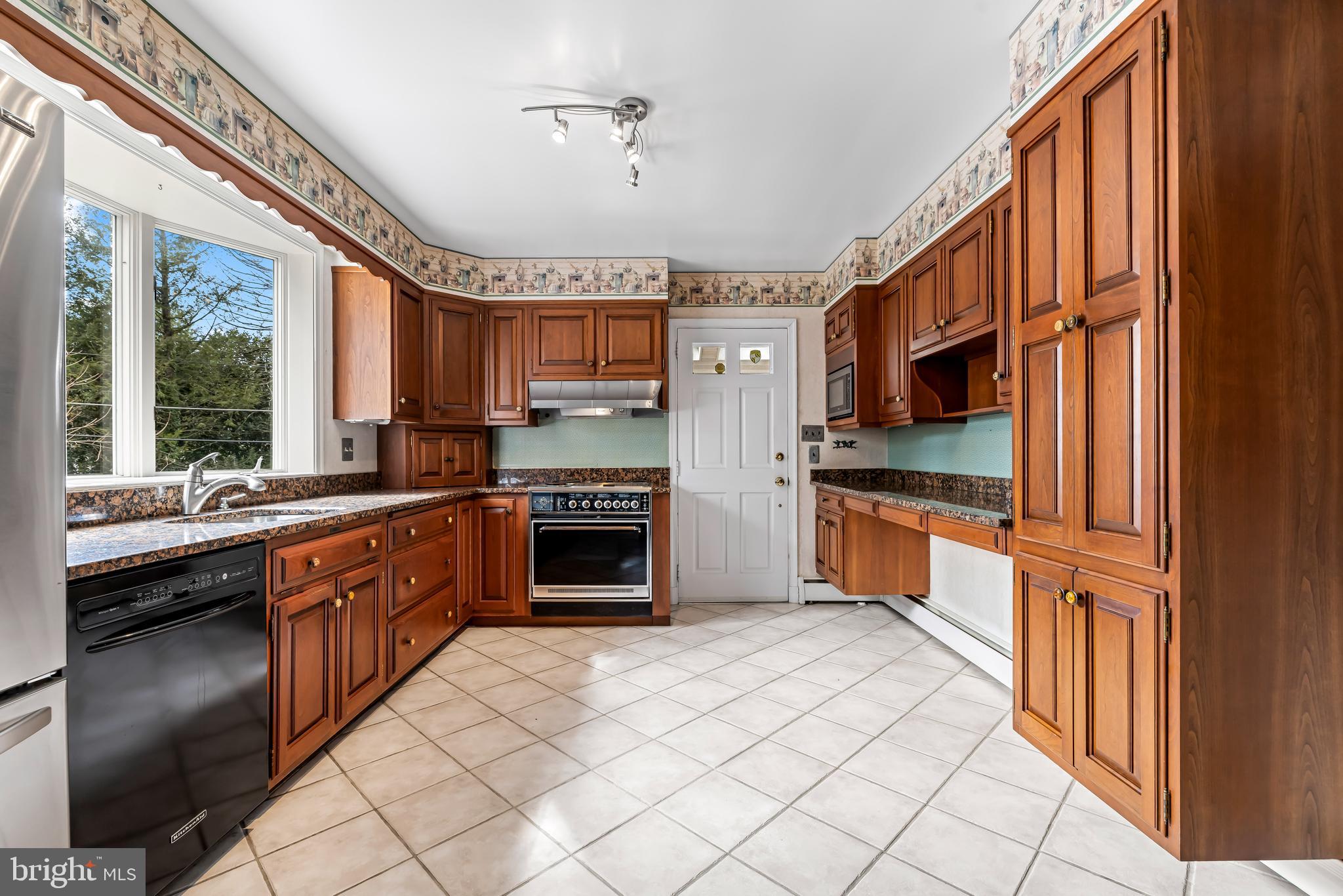 1607 Ruxton Road Towson, MD 21204 - Photo 12 of 46 a kitchen with stainless steel appliances granite countertop a refrigerator a sink dishwasher a stove and white countertops with wooden floor