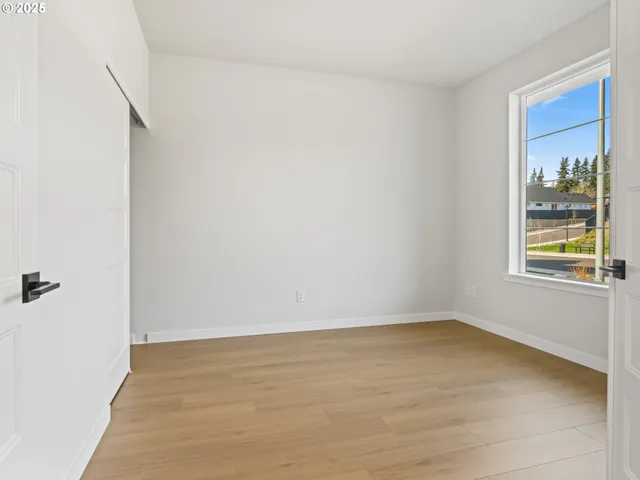a view of an empty room with a window and wooden floor