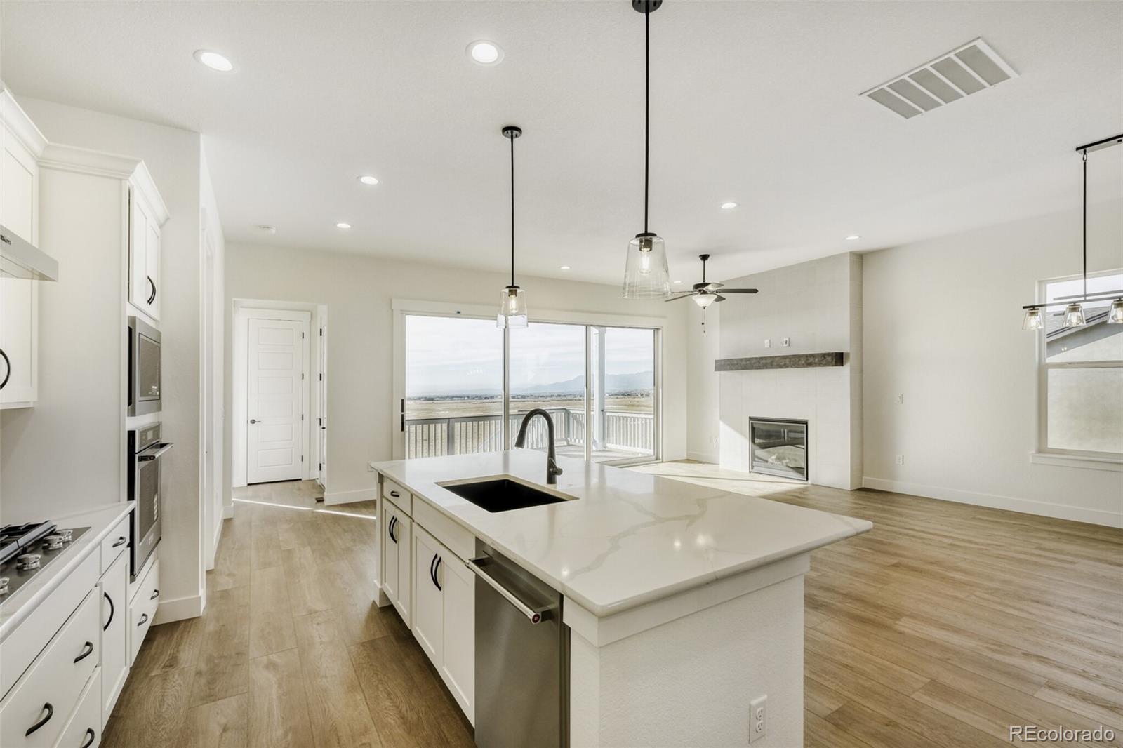 9659 Owl Perch Loop Colorado Springs, CO 80908 - Photo 13 of 28 a kitchen with stainless steel appliances granite countertop a sink a stove and a wooden floor