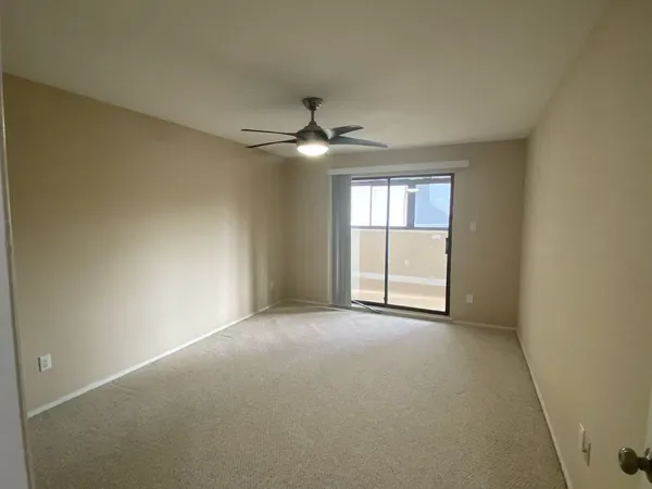 an empty room with chandelier fan and windows