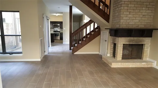 a view of an empty room with wooden floor and a fireplace