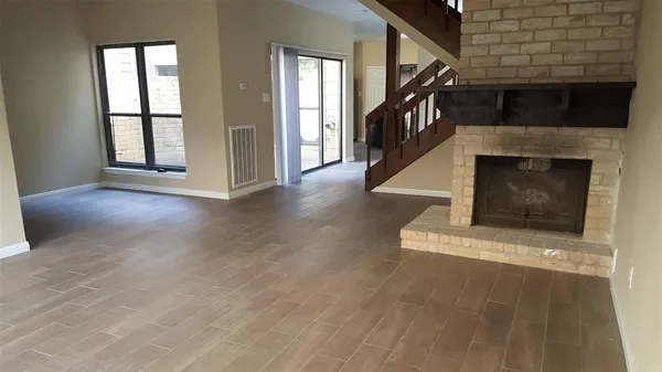 a view of an empty room with wooden floor fireplace and a window
