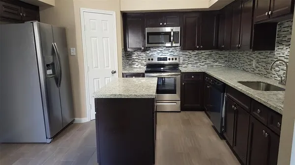 a kitchen with stainless steel appliances granite countertop a refrigerator a stove a sink and a microwave