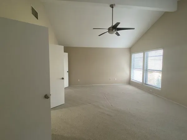 an empty room with windows and fan