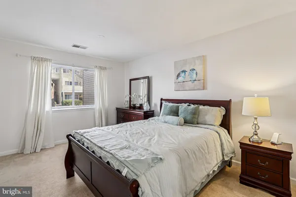 a bedroom with a bed and a lamp on dresser
