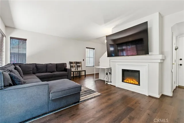 a living room with furniture a flat screen tv a fireplace and wooden floor