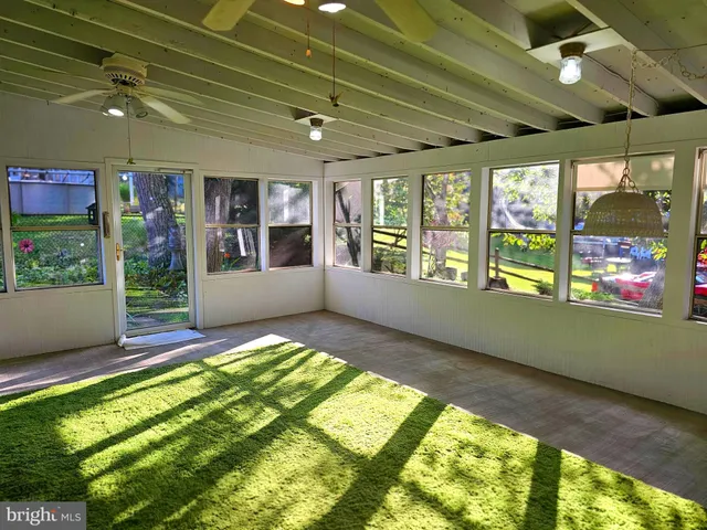 an empty room with windows and chandelier fan