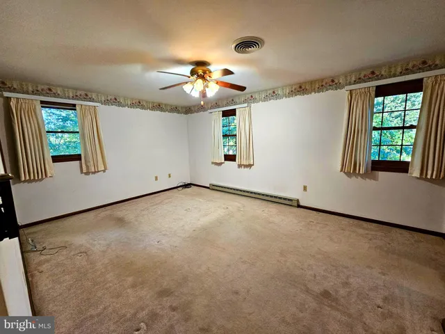 an empty room with windows and fan