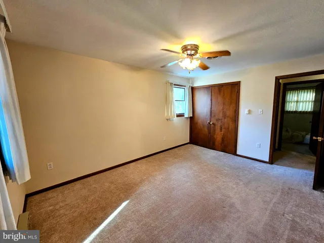 an empty room with windows and chandelier fan
