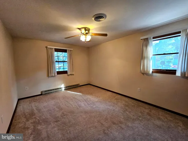 an empty room with windows and fan