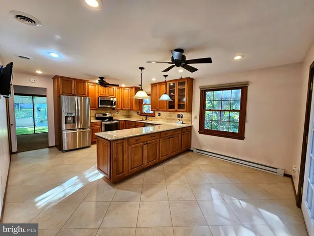 a kitchen with stainless steel appliances kitchen island granite countertop a refrigerator and a sink
