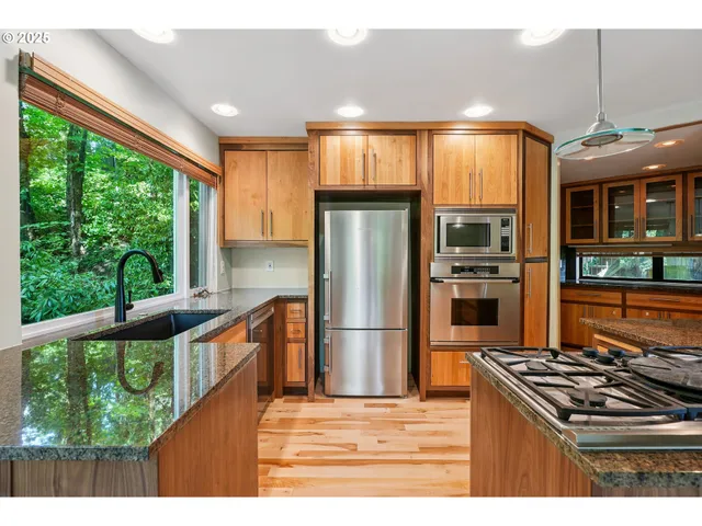 a kitchen with stainless steel appliances granite countertop a refrigerator a stove and a wooden floors