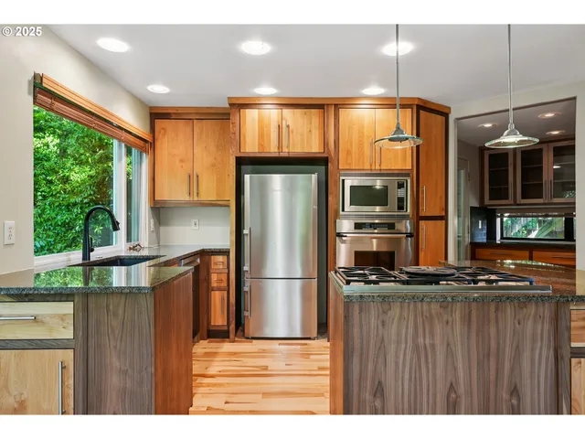a kitchen with stainless steel appliances granite countertop a refrigerator a sink and a stove