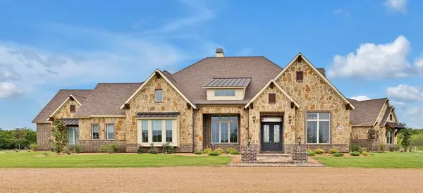 a view of a brick house next to a yard with large trees