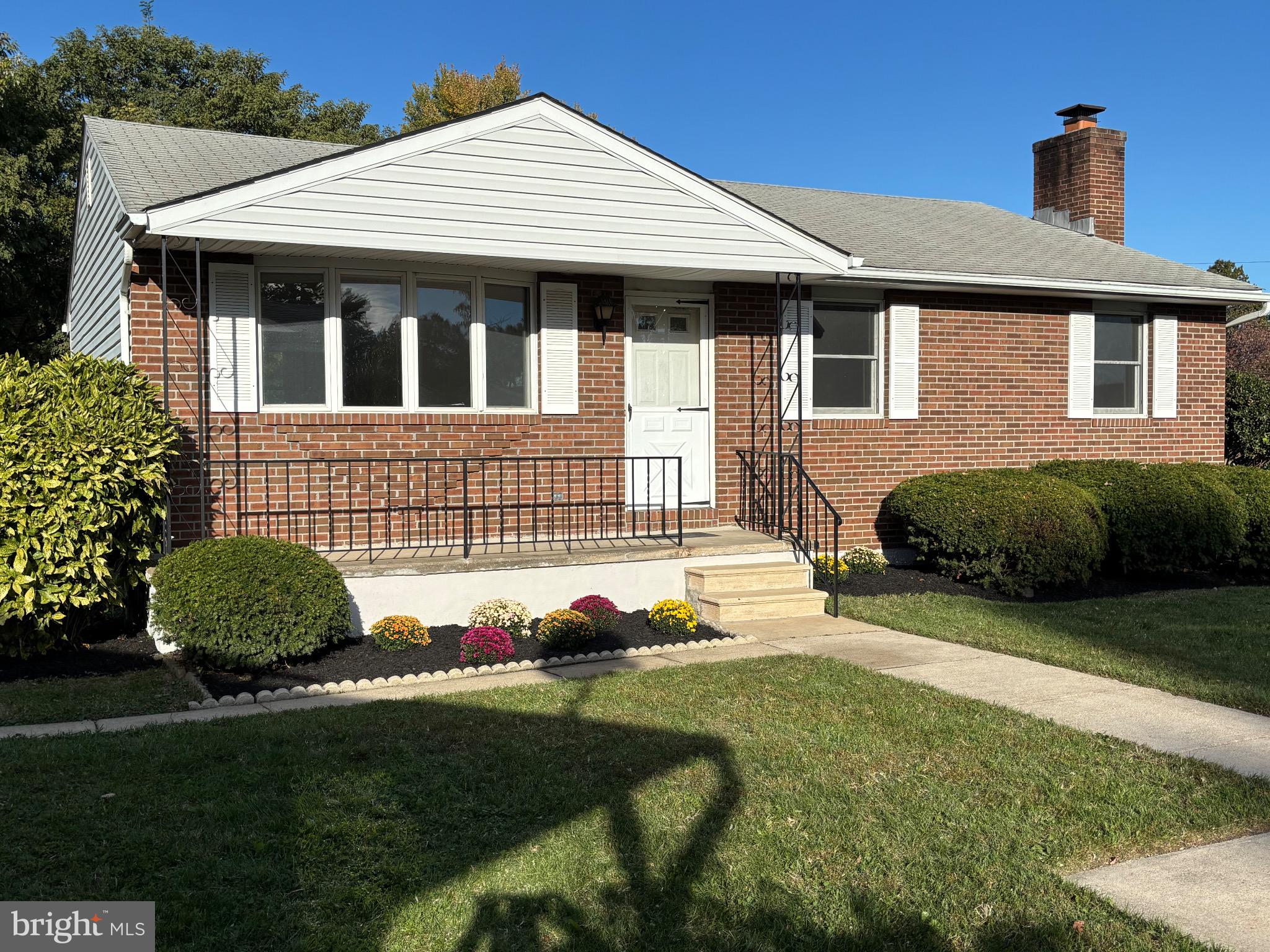 Charming brick home with vibrant landscaping.