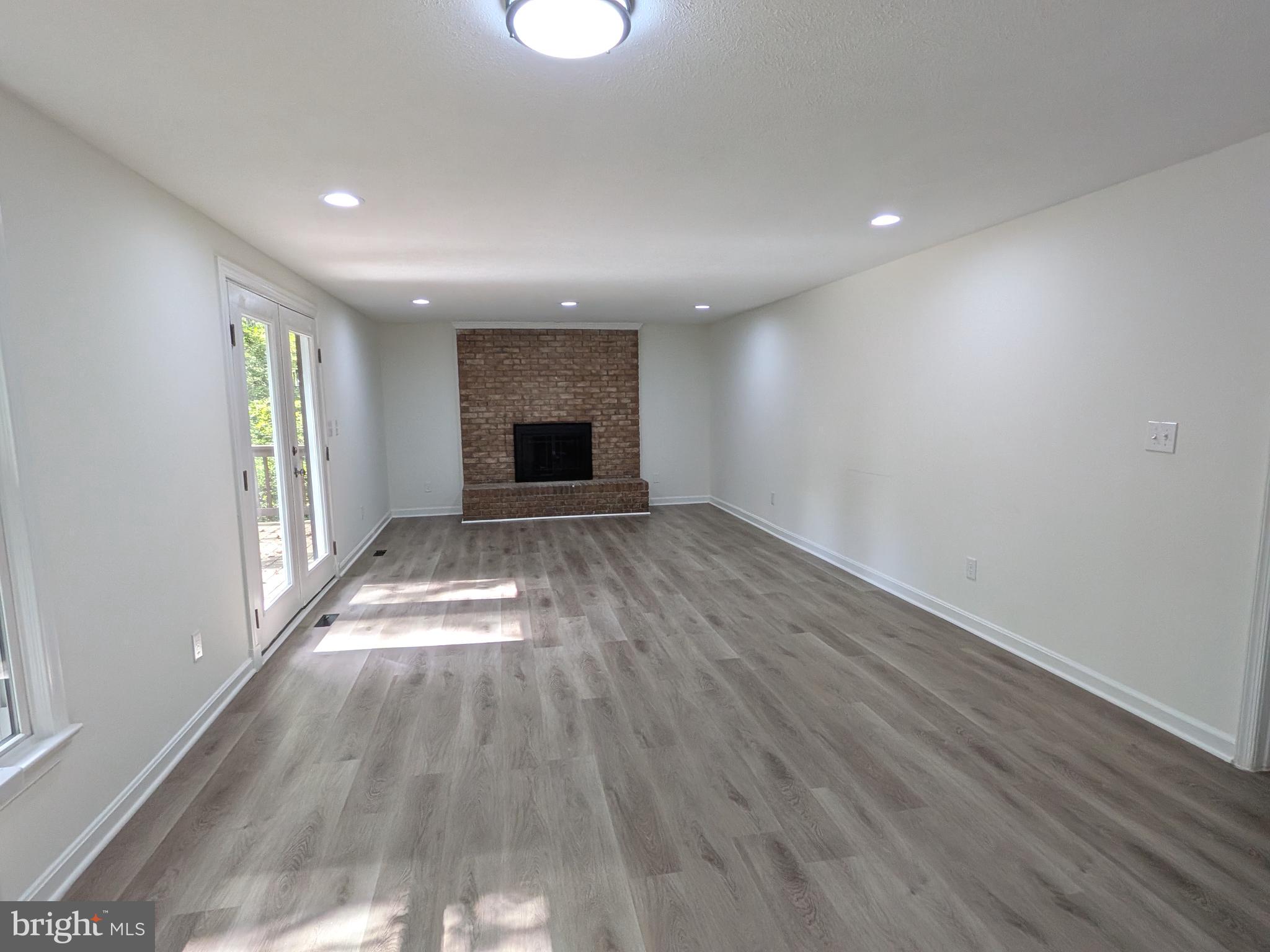 1019 Isabella Drive Stafford, VA 22554 - Photo 8 of 20 an empty room with wooden floor fireplace and windows