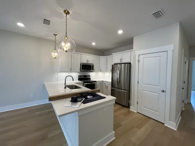 a view of a room with kitchen island stainless steel appliances wooden floor and window