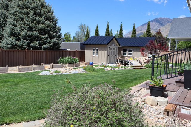 1055 North 1000 East Mapleton, UT 84664 - Photo 88 of 112 Expansive backyard featuring a manicured lawn, a detached shed with a black metal roof, and a decorative garden bridge