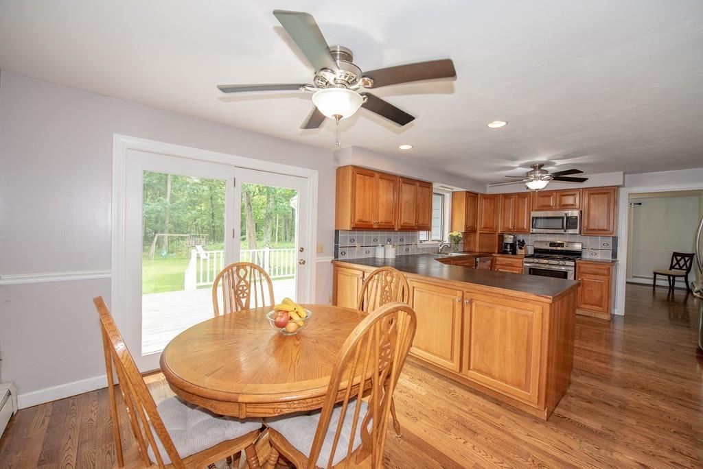 195 Kaleva Road Lancaster, MA 01523 - Photo 15 of 39 a kitchen with stainless steel appliances granite countertop a stove a refrigerator a dining table and chairs with wooden floor