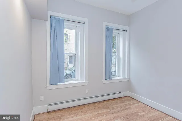 a view of a hallway with wooden floor and a bathroom