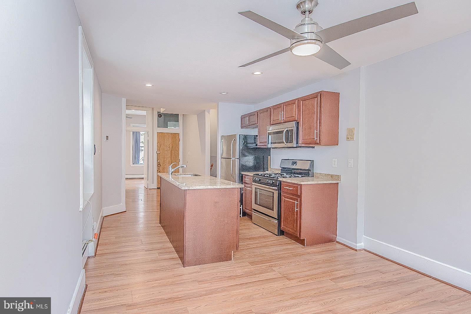 2022 Ogden Street Philadelphia, PA 19130 - Photo 5 of 44 a kitchen with stainless steel appliances granite countertop a stove top oven a sink a refrigerator and white cabinets with wooden floor