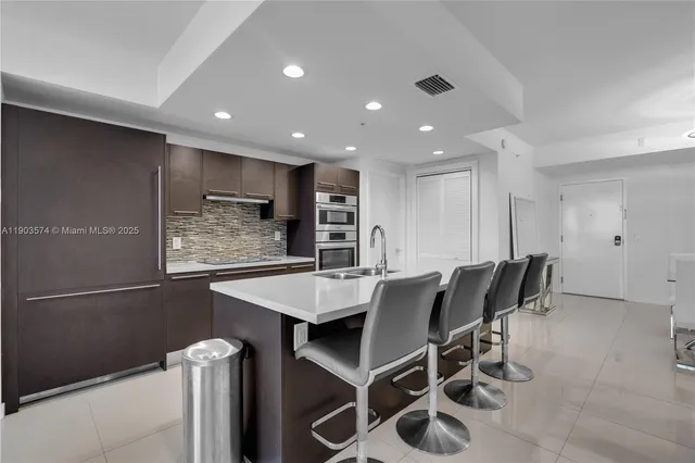 a kitchen with stainless steel appliances kitchen island granite countertop a table chairs sink and cabinets