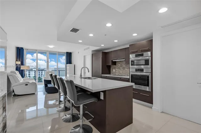 a kitchen with stainless steel appliances kitchen island granite countertop a table chairs and a refrigerator