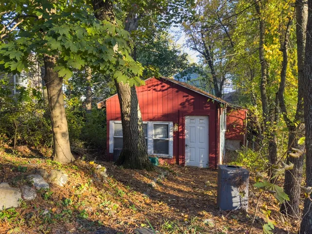 a backyard of a house with large trees and wooden fence